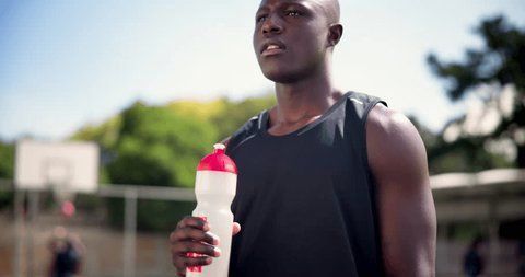 En svett atlet med vannflaske ser bort, sannsynligvis en fotballspiller.